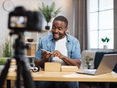 African man filming video while unpacking new smartphone