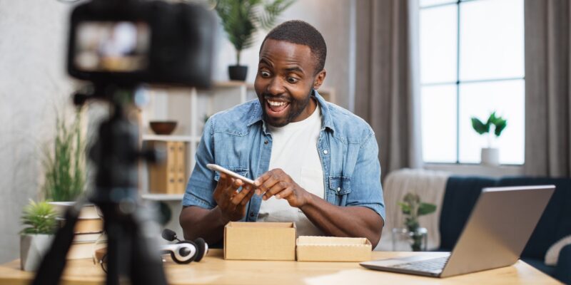 African man filming video while unpacking new smartphone