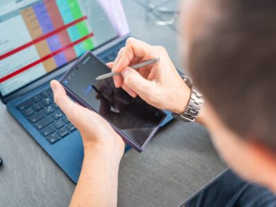 Close up view of man hand holding smart phone and stylus pen at his creative workspace.