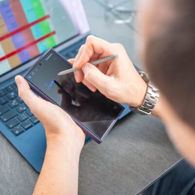 Close up view of man hand holding smart phone and stylus pen at his creative workspace.