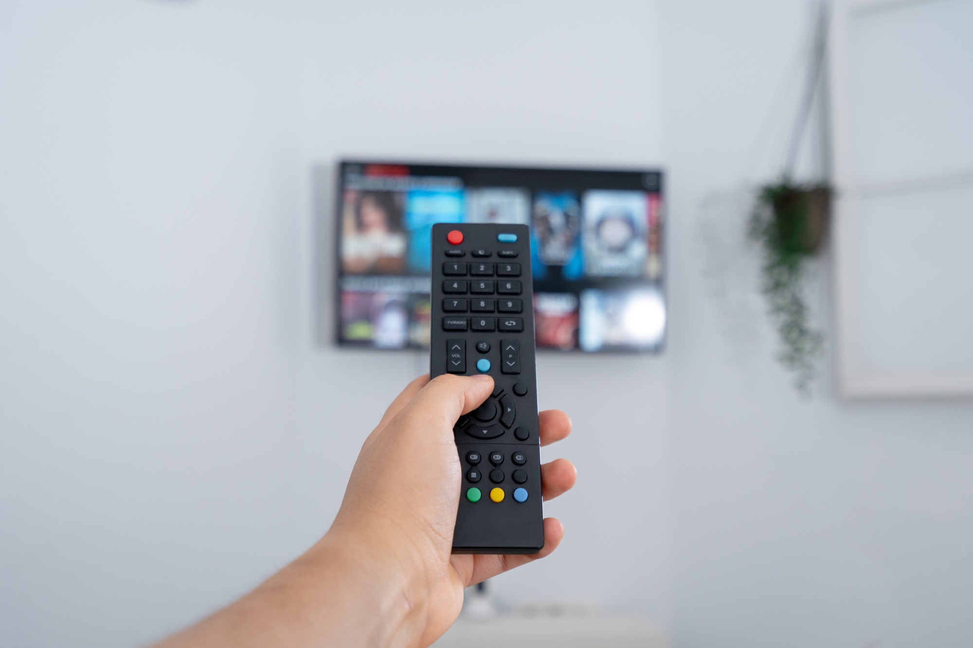 Hand holding remote control, changing channels on smart tv