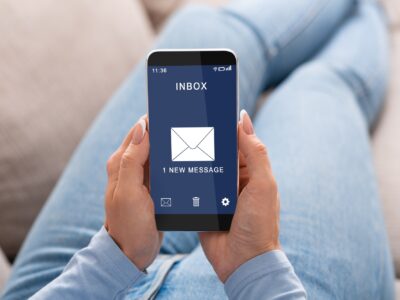 Woman Reading E-Mail Message On Smartphone Sitting On Couch Indoor